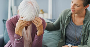 elderly woman being comforted by adult daughter. Dementia symptoms concept