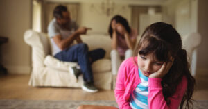 sad girl with parents arguing in background