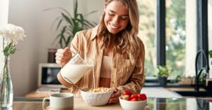 woman pouring milk into a bowl of cereal