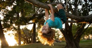 child hanging from tree branch