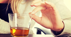 'Diagnosed Psychopath 'Reveals Reality of What Being Drunk Feels Like For Her hand touching rim of glass
