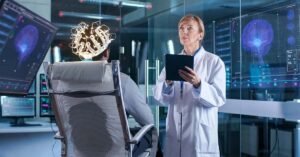 In World First, Researchers Claim They Can ‘Unlock New Dimensions’ After Two People ‘Chat’ While Dreaming Man Wearing Brainwave Scanning Headset Sits in a Chair while Scientist with Tablet Computer Supervises Process. In the Modern Brain Study Laboratory Monitors Show EEG Reading and Brain Model.