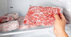 person taking frozen meat out of a freezer