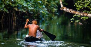 Never-Before-Seen Images of Uncontacted Amazon Community Unveiled Member of Amazon tribe canoeing down river