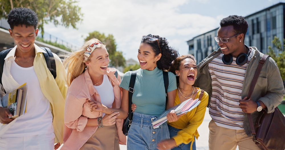 Walking, laughing and students at university with fun for learning, bonding and talking. People, diversity and group of gen z friends outdoor with books ready for education at college campus.
