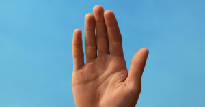 Hand raised in air, sky blue background
