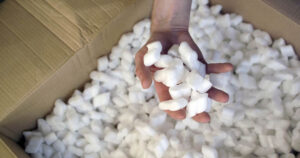 Latest TikTok Trend Has People Eating Packing Peanuts, Health Experts Weigh In hand grabbing packing peanut from a cardboard box full of them