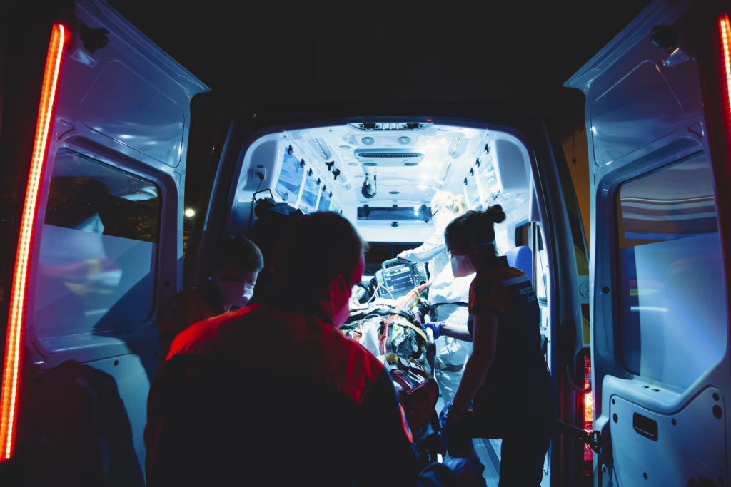 Emergency medical personnel attend to a patient inside an ambulance at night, highlighting the critical nature of responding to meningitis symptoms. The scene captures the urgency and professionalism required when dealing with such life-threatening conditions, as paramedics work diligently to provide immediate care.