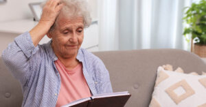 Elderly woman confused with hand placed on head. Dementia symptoms concept