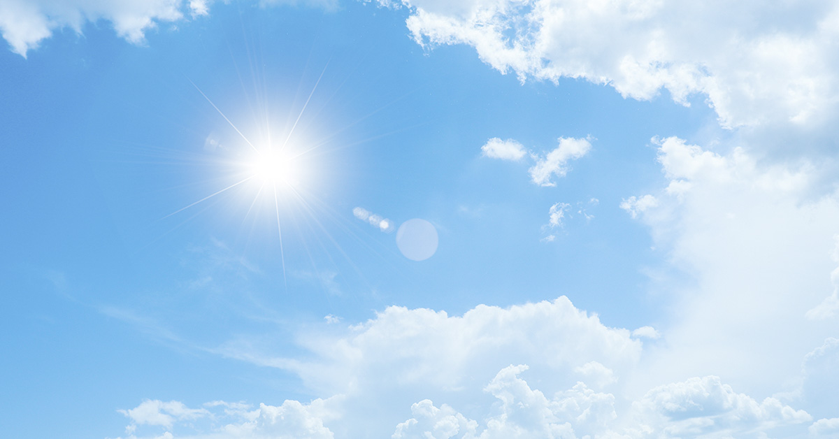 Sun shining in blue sky with some white clouds