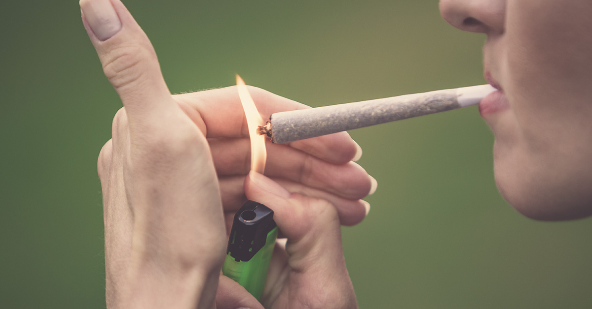 person lighting a marijuana joint