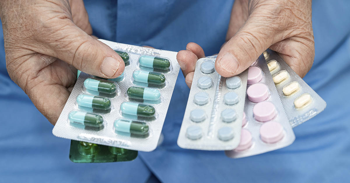 person holding several blister packs containing medications