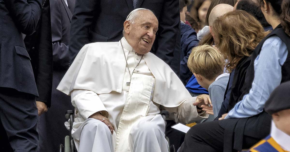 Pope Francis in a wheel chair happily speaking with people