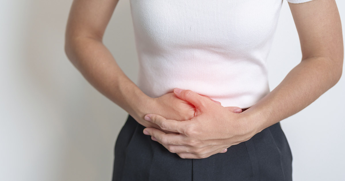 woman with hands placed over lower abdomen in pain