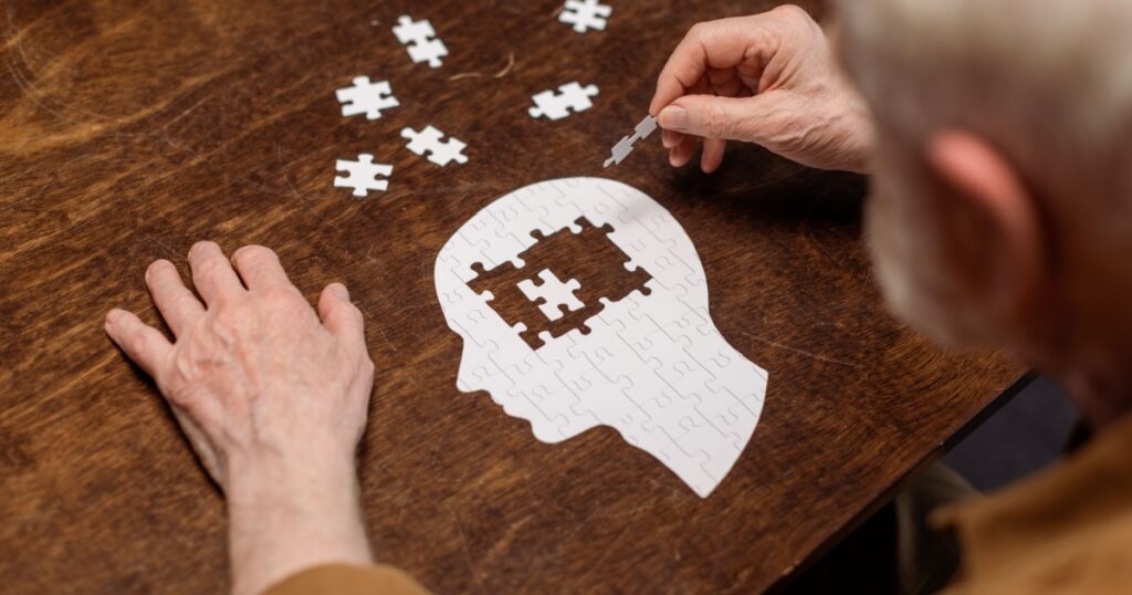 high angle view of senior man collecting jigsaw puzzle as dementia rehab
