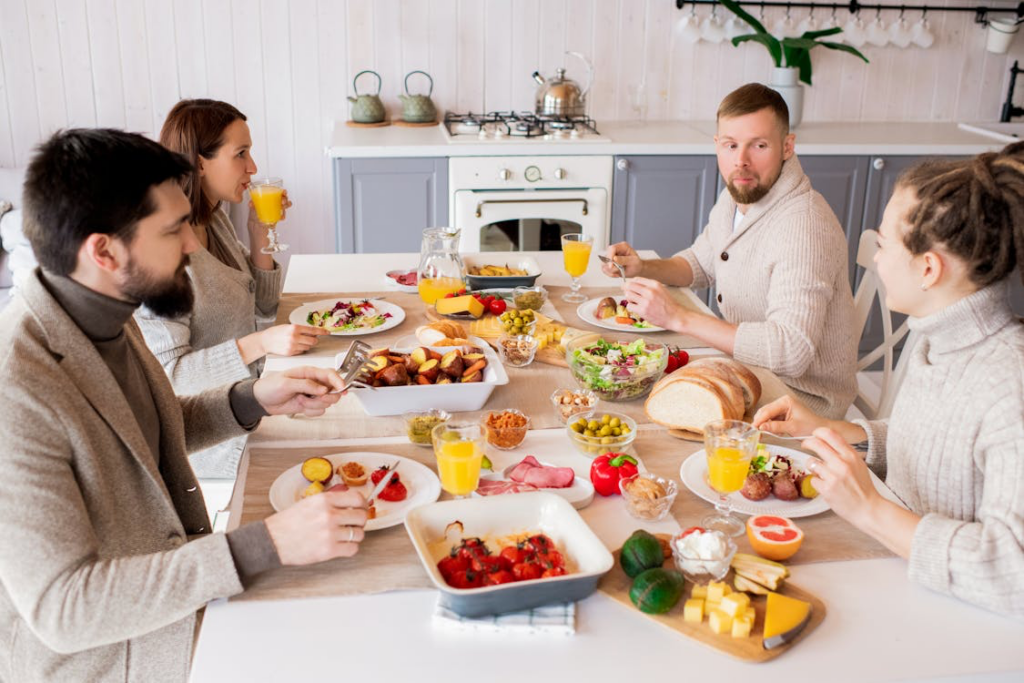 Family gathering around a table filled with fresh, colorful dishes, sharing a meal made from minimally processed ingredients - illustrating the social and nutritional benefits of whole food eating that Dr. Smith now recommends.