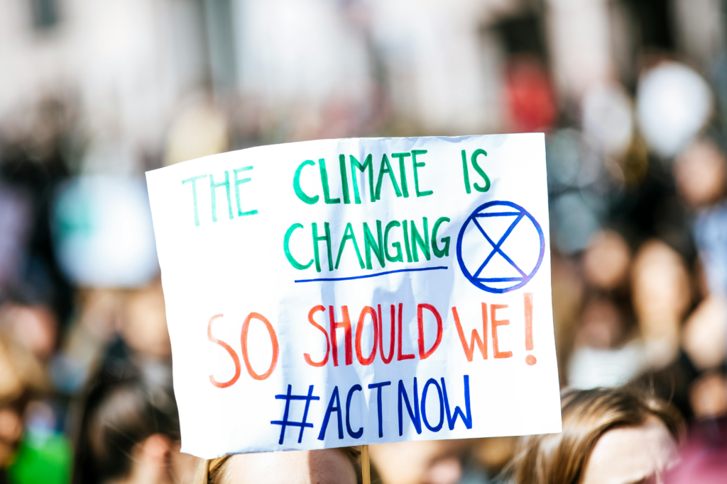 Climate change protest sign reading 'The climate is changing, so should we!' highlighting modern threats to ancient marine ecosystems.