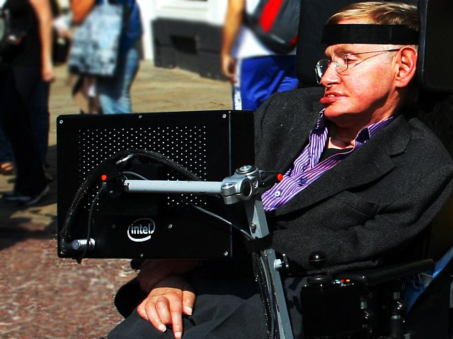A renowned physicist Stephen Hawking in his wheelchair with his specialized computer communication system. Hawking, who lived with ALS for several decades, is using the speech-generating device that allowed him to communicate despite losing his ability to speak. The computer mounted to his wheelchair features an Intel processor and represents the adaptive technology that helps ALS patients maintain communication abilities as their condition advances.