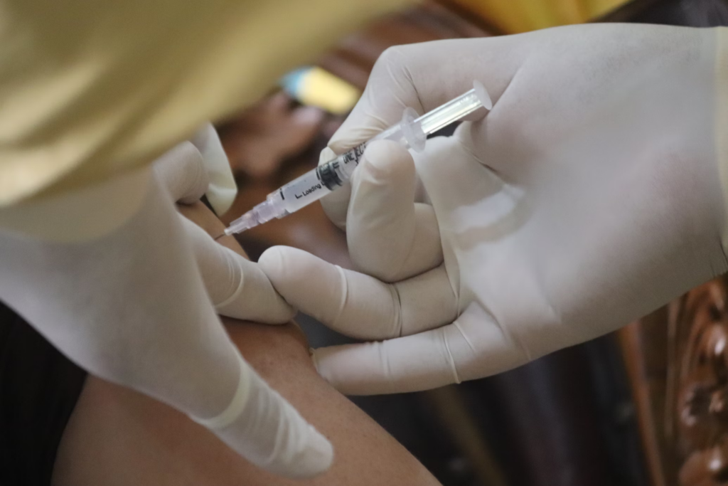 Close-up of gloved hands administering an injection, showing proper technique for delivering medication via syringe.