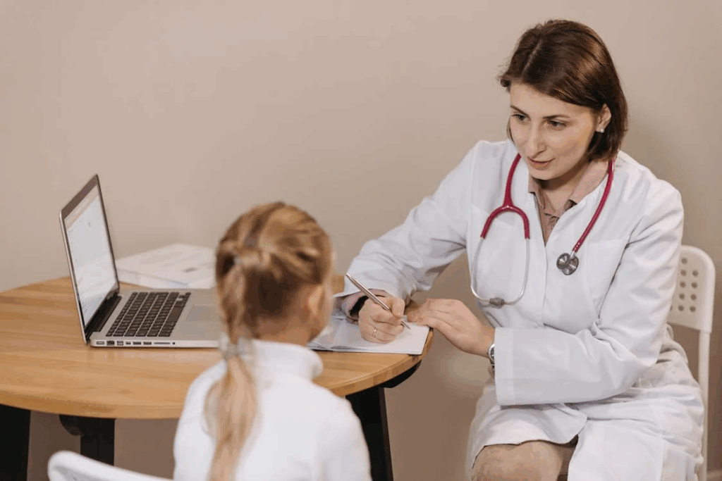 Woman in White Lab Coat Listening to a Girl and Writing Down Notes