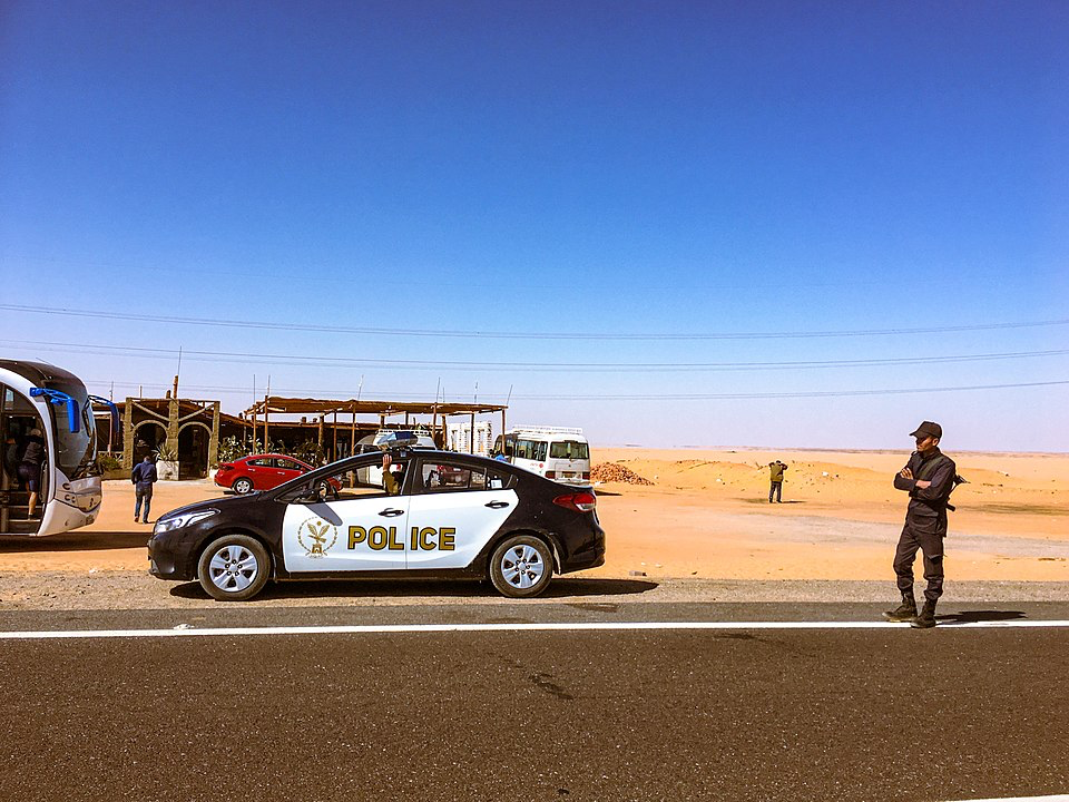 Egyptian police vehicle and officers stationed in a desert area near tourist facilities outside Cairo. This roadside checkpoint illustrates the law enforcement response that can occur when witnessing donkey abuse leads to confrontation, as in the case of Dutch animal activist Joke Van der Post. The stark desert landscape and official police presence highlight the serious legal implications of intervening in animal mistreatment cases in Egypt.