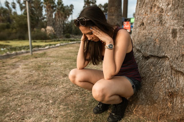 woman kneeling by a tree, stressing out
