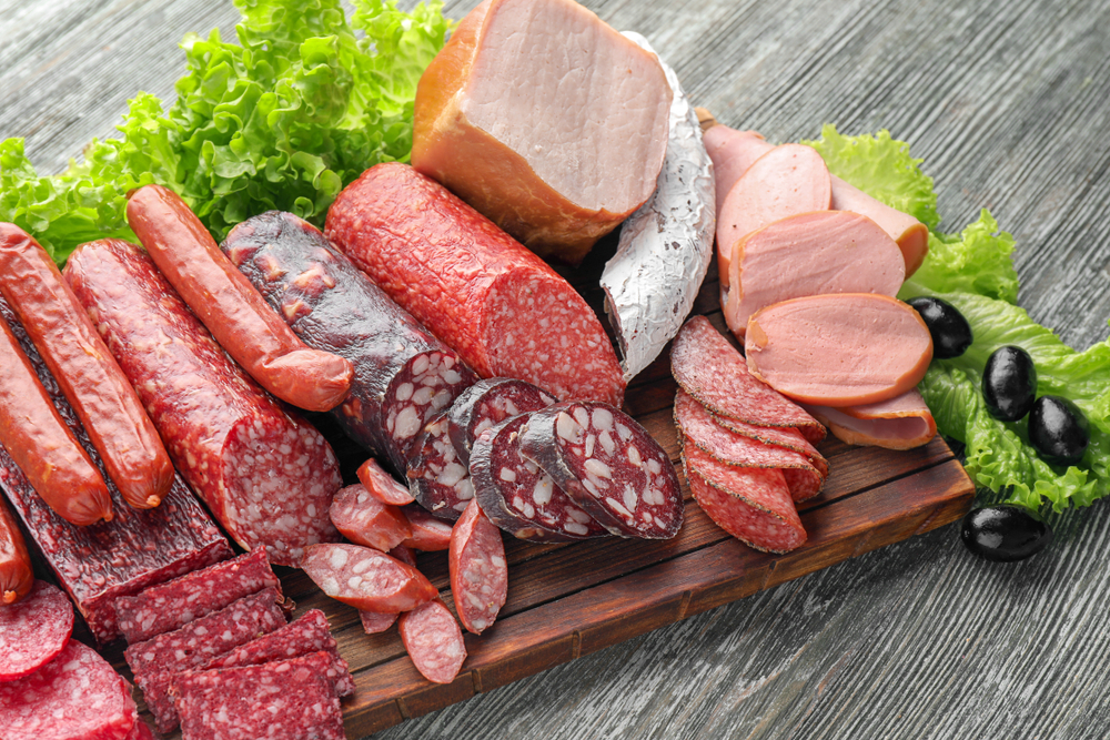 Assortment of delicious deli meats on wooden board