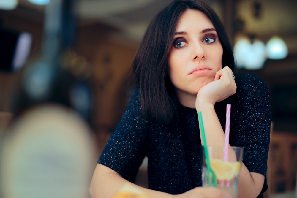 Bored Woman Having a Lemonade at a Party. Unhappy girl feeling bored having a drink while waiting