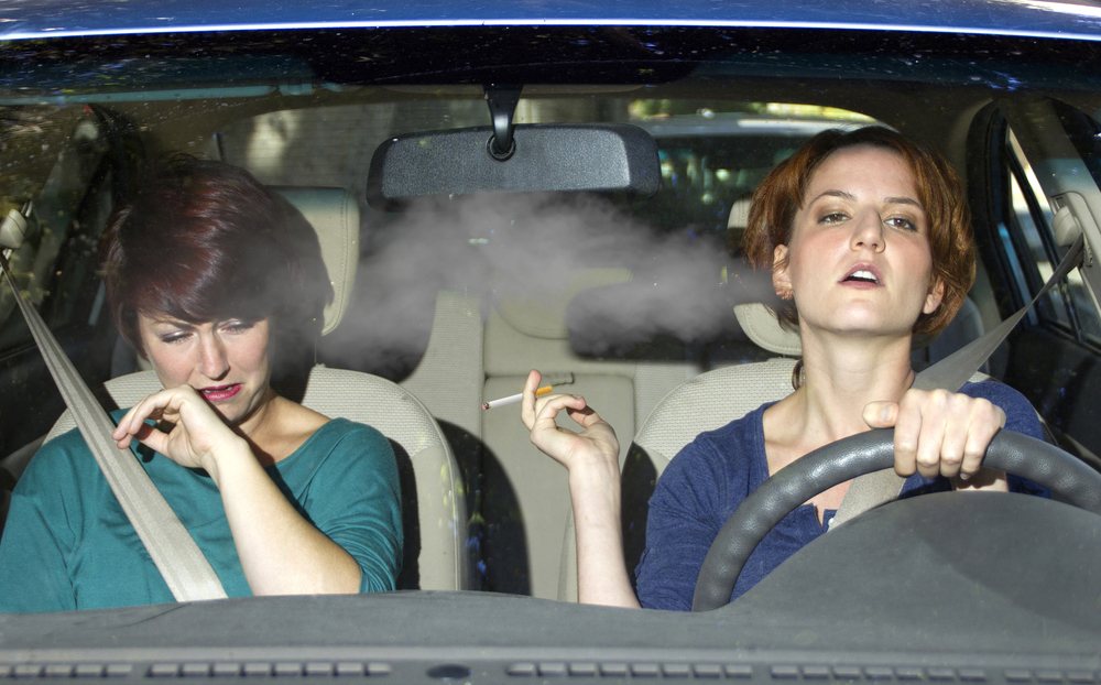 young female smoking while driving inside the car