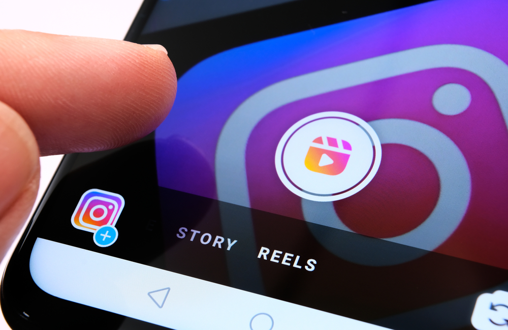 Stone / UK - August 31 2020: Instagram Reels seen in Instagram app on mobile phone and finger pointing at it. New feature from Facebook aimed to create competition with TikTok.