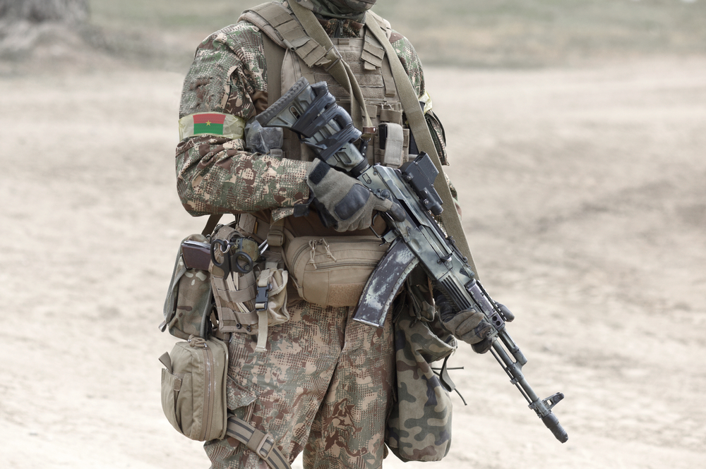 Soldier with assault rifle and flag of Burkina Faso on military uniform. Collage.
