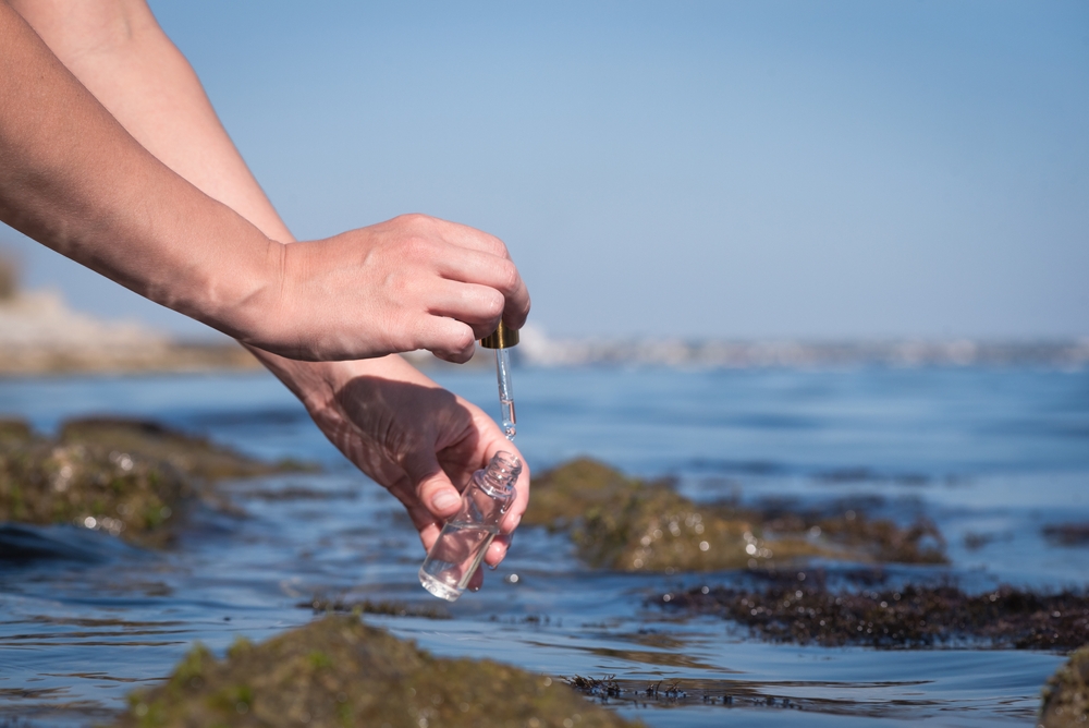Sea water pollution concept. The scientist is taking water sample of sea water close up concept.