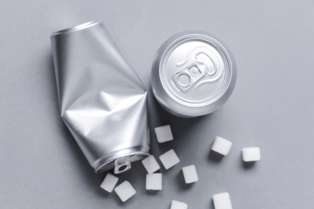 Cans of soda and sugar on grey background. Diabetes concept
