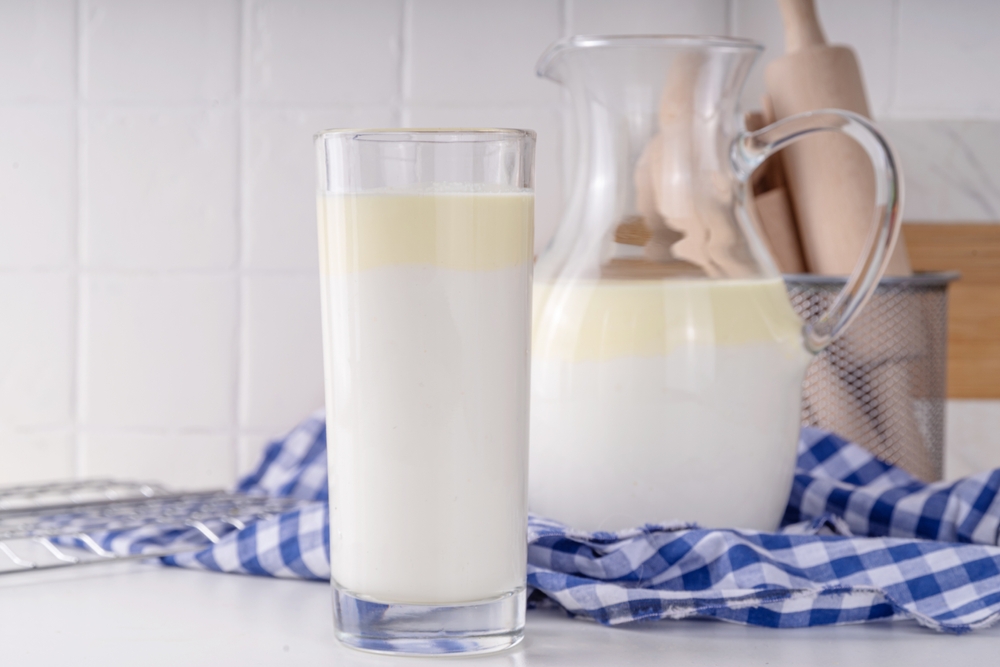 Non-Homogenized, whole milk, cream-top layered dairy product, Creamline Milk concept. Organic farm natural, unpasteurized milk in glass and jug, on white kitchen table copy space