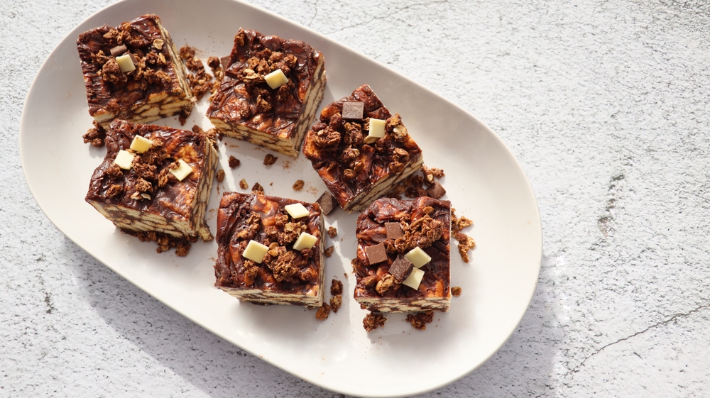 Lazy cake or mosaic cake with granola and chocolate . Homemade no bake chocolate biscuit cake on a table .