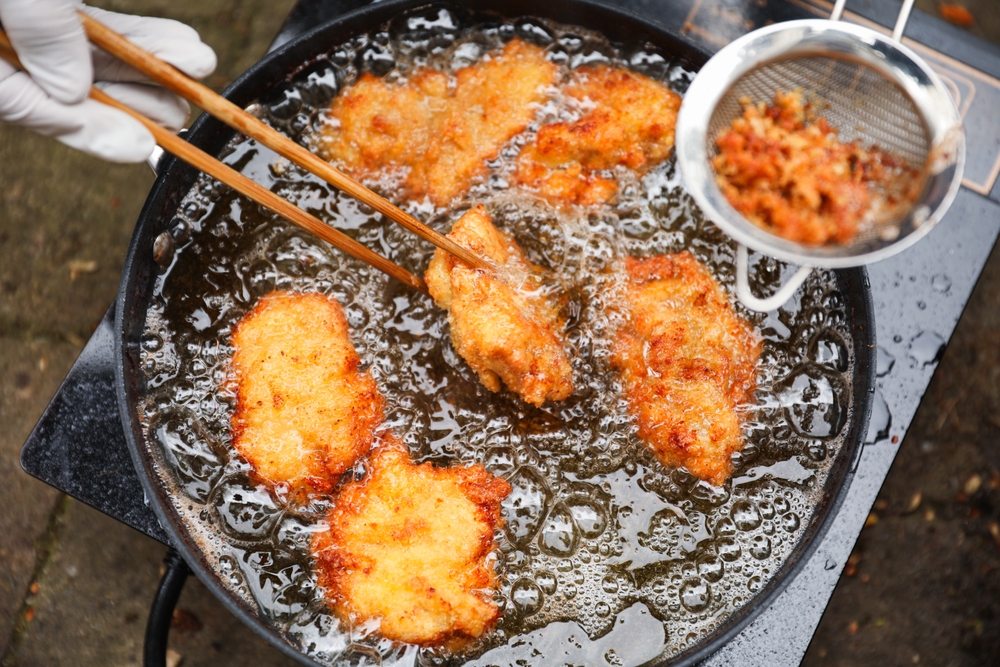 golden, crispy fried chicken pieces in bubbling oil, symbolizing indulgence and temptation