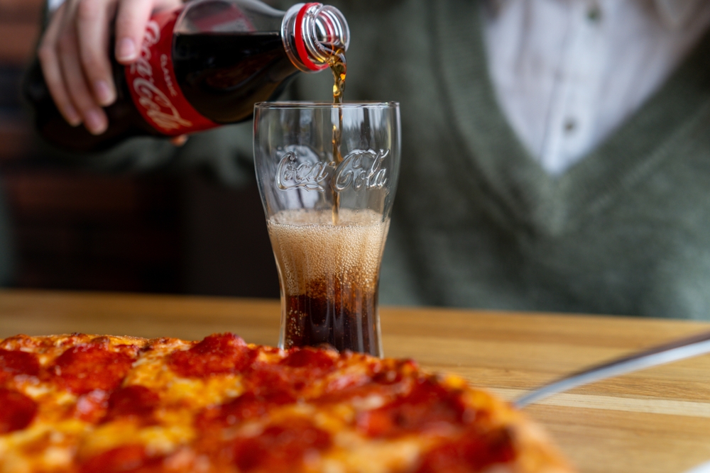 MINSK, BELARUS - JANUARY 26, 2020: Pouring coca cola into a glass at the dining table
