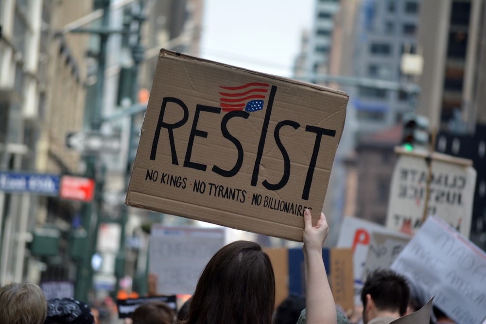 NEW YORK, NEW YORK USA - April 19, 2025: People holding signs at an Anti-Trump protest against the current administration's actions on immigration and civil rights in Midtown Manhattan.
