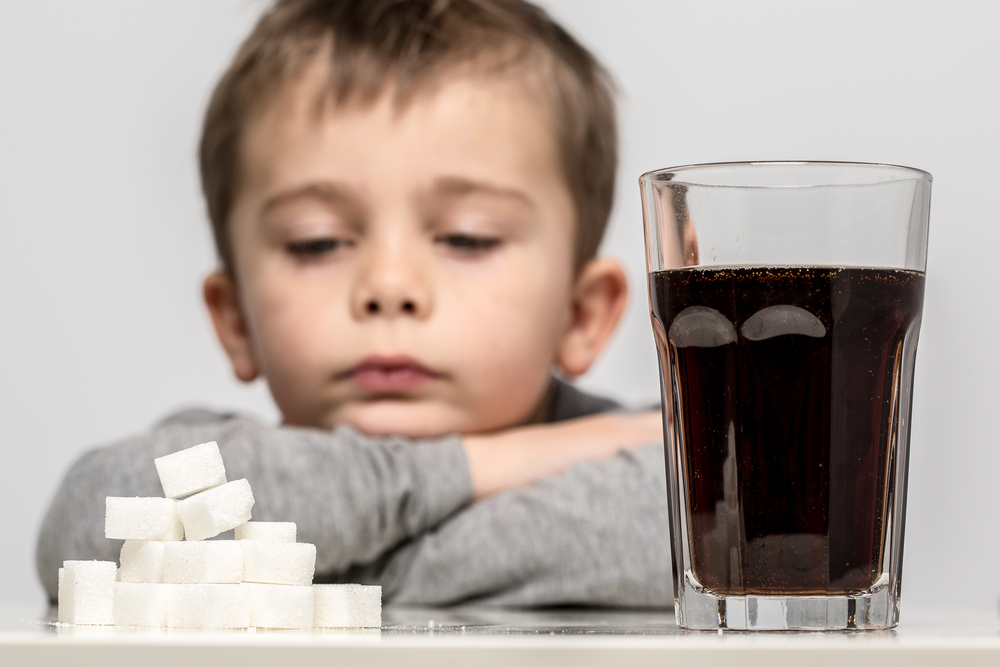 Glass full of soft drink, next to it is the amount of sugar used in it. Modern day to day diet, young people drinking to many soft drinks, everyday sugar usage among children concept photo.