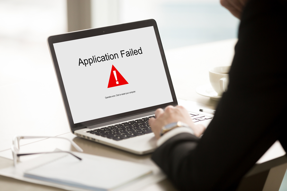 Application failed, businessman having problem with laptop, bad software failure on screen, broken computer stopped working in office, hanging pc caused system crash error message, close up rear view