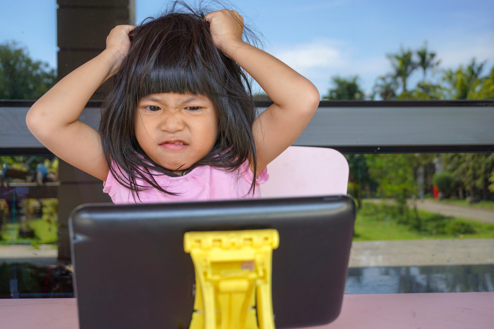 Angry Asian cute girl screaming because her mother try to take her tablet away. Stressed child, Kid with attention deficit hyperactivity disorder (ADHD) can't handle her emotion.