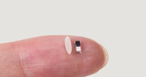 world's smallest pacemaker on the tip of a finger being compared to grain of rice for size comparison