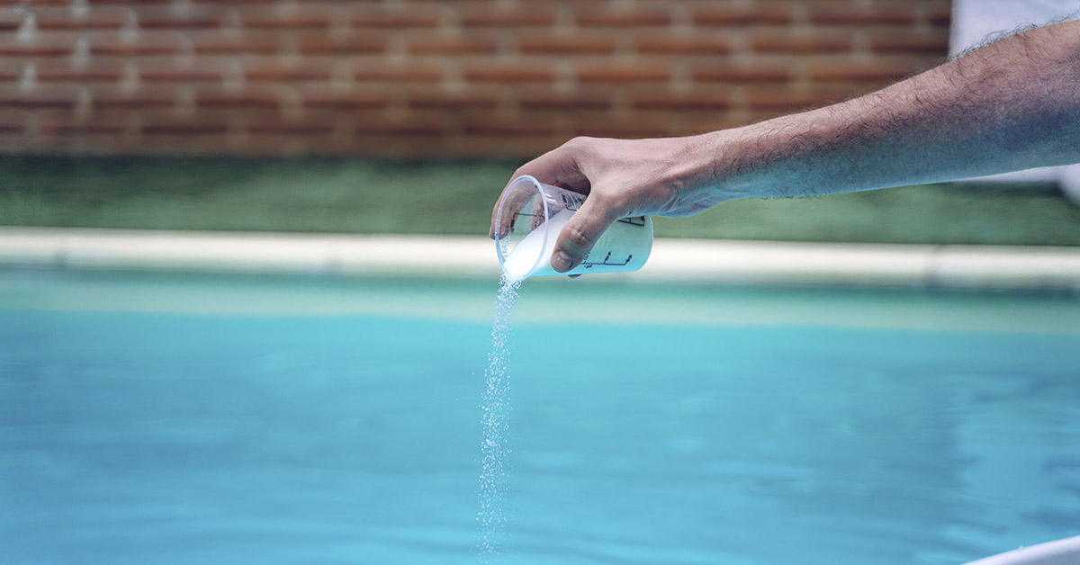 person pouring powdered chlorine into a pool