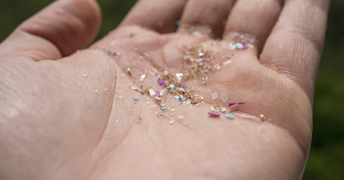 Various pieces of tiny plastic in palm of hand. Microplastic concept
