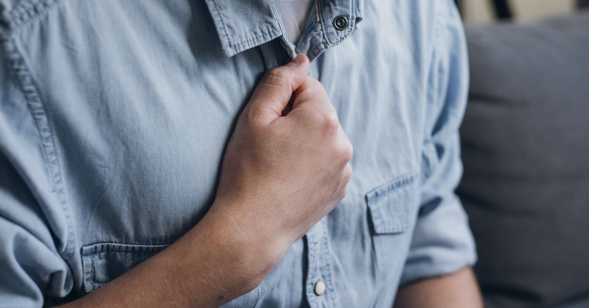man with hand in fist placed over chest. signs of heart trouble concept