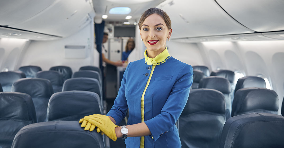 Flight attendant standing in the aisle on an empty passenger jet