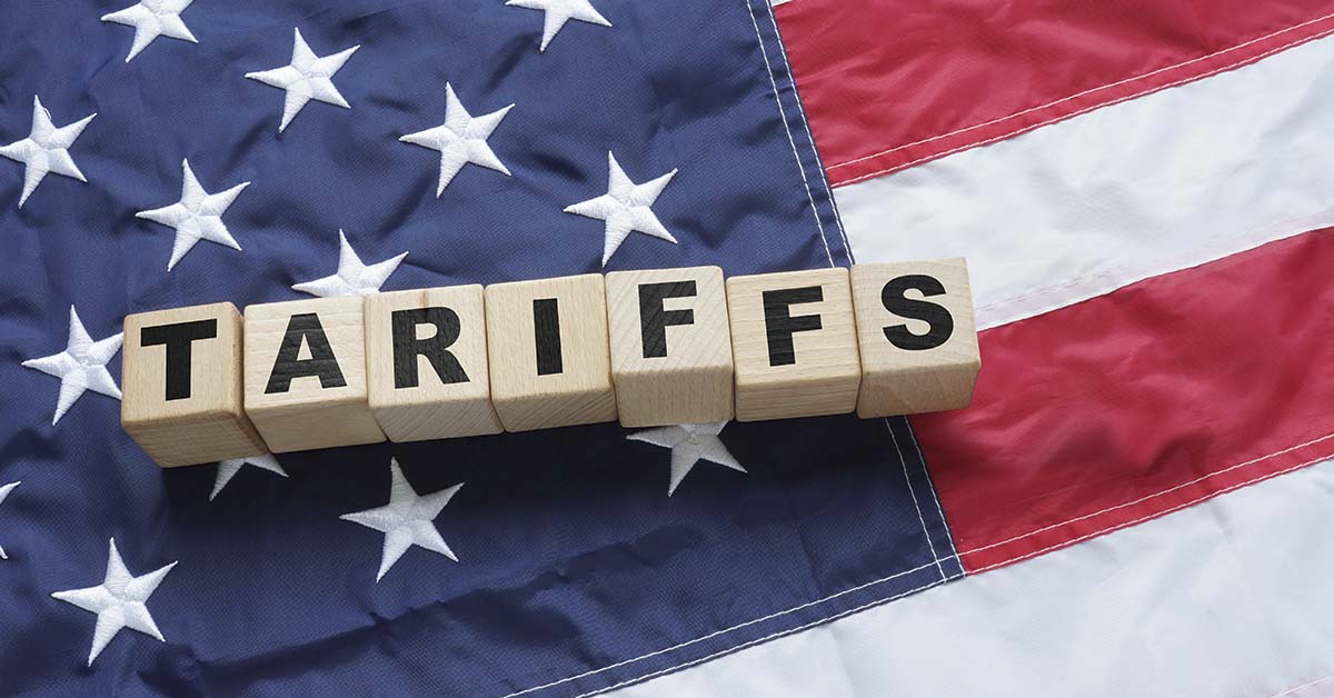 Tariffs written on wooden blocks sitting on an American Flag.