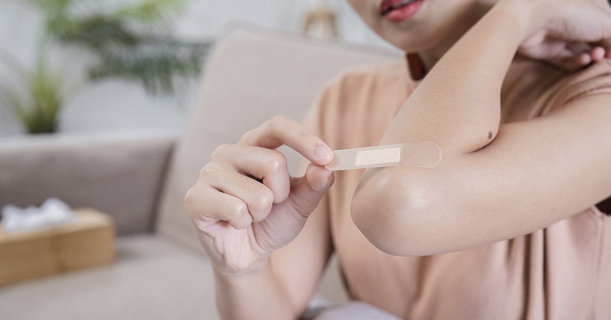 woman putting band-aid on her elbow