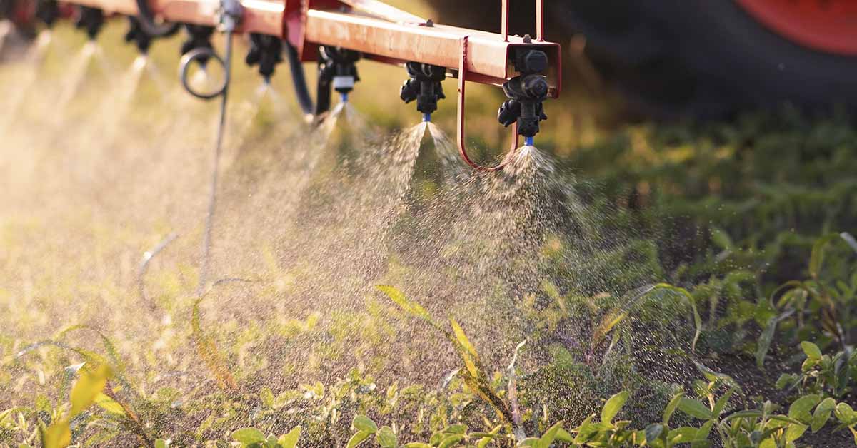 Pesticides being sprayed on crops from farming machinery