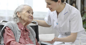 Hospice Chef Reveals the Most Requested Last Meal by Patients elderly woman in a wheel chair being comforted by a nurse. Hospice concept